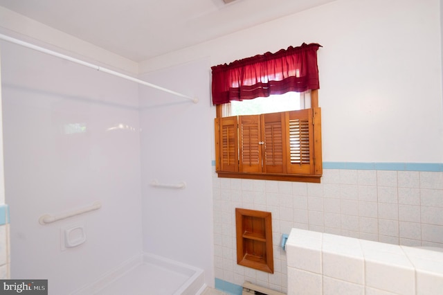 bathroom with a shower and tile walls