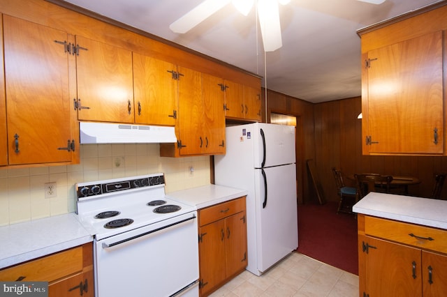 kitchen featuring ceiling fan, wood walls, white appliances, and decorative backsplash