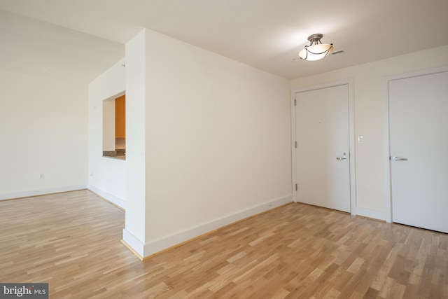 unfurnished room featuring light wood finished floors, visible vents, and baseboards