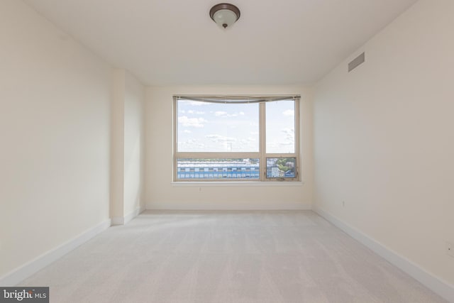 spare room featuring visible vents, light colored carpet, and baseboards