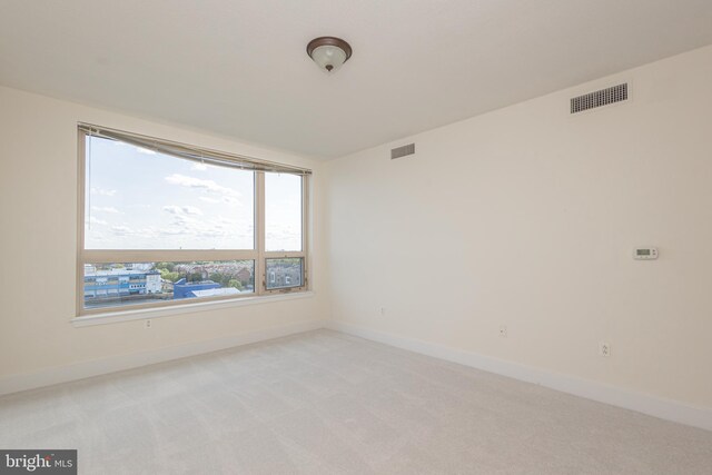 unfurnished room featuring light colored carpet, visible vents, and baseboards