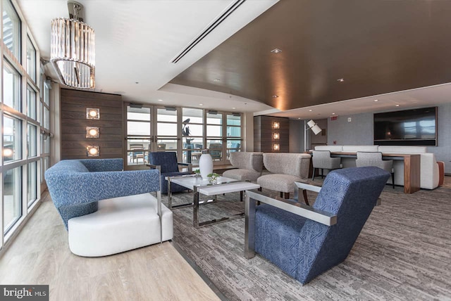 living room featuring wood finished floors, a tray ceiling, recessed lighting, floor to ceiling windows, and a notable chandelier