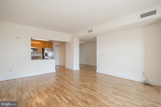 unfurnished living room with visible vents, baseboards, and light wood-style flooring