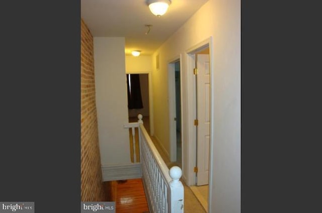 corridor featuring brick wall and hardwood / wood-style flooring