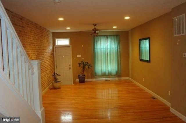 interior space with brick wall, ceiling fan, and light hardwood / wood-style floors