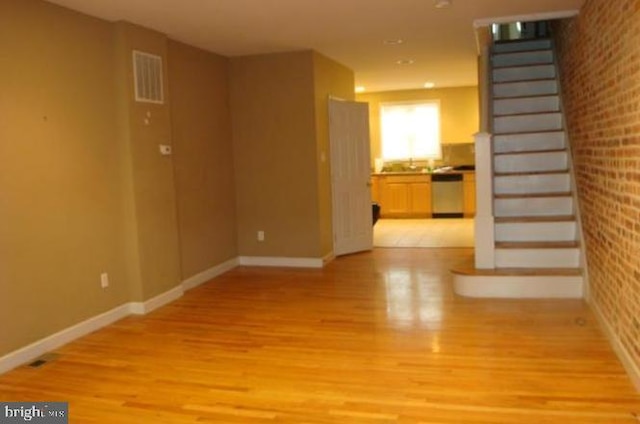 spare room with light wood-type flooring and brick wall