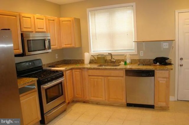 kitchen with light stone counters, a wealth of natural light, stainless steel appliances, and sink