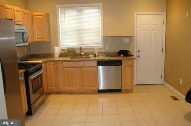 kitchen featuring stainless steel appliances, sink, light tile patterned floors, and light brown cabinetry