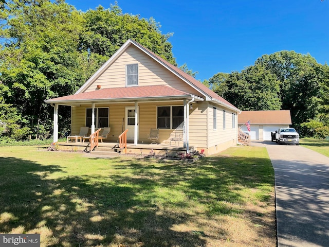 view of front of house featuring an outdoor structure, a garage, a porch, and a front lawn