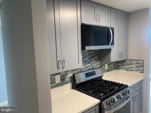 kitchen with decorative backsplash, appliances with stainless steel finishes, and gray cabinets