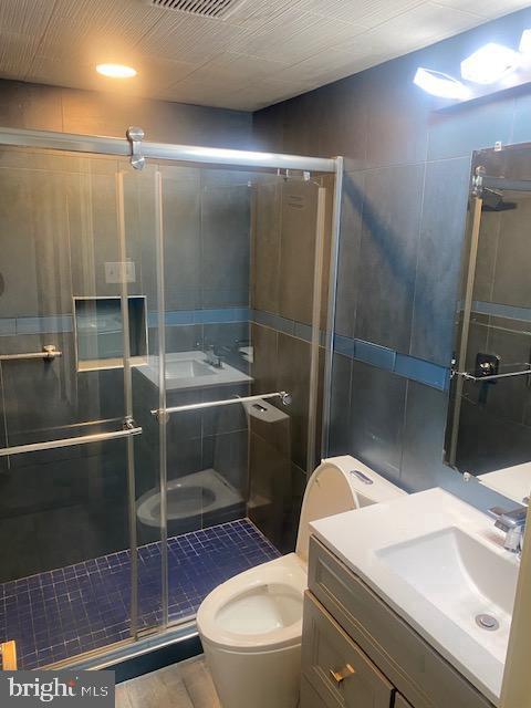 bathroom with a shower with door, vanity, and toilet