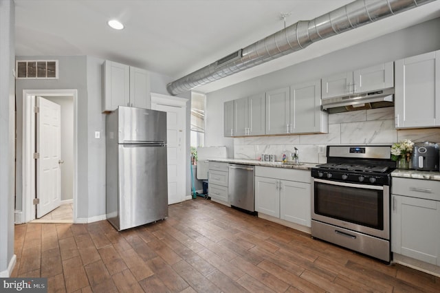 kitchen with white cabinetry, appliances with stainless steel finishes, dark wood-type flooring, and tasteful backsplash