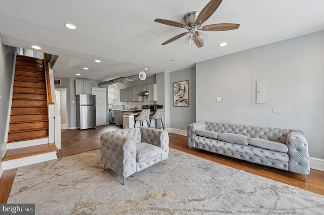 living room featuring ceiling fan, electric panel, and hardwood / wood-style floors