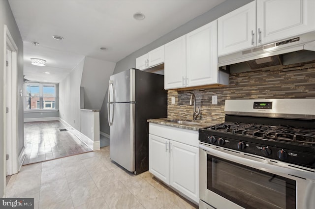 kitchen with sink, appliances with stainless steel finishes, white cabinets, dark stone counters, and backsplash