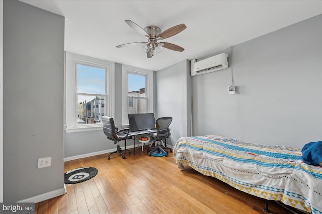 bedroom with hardwood / wood-style floors, an AC wall unit, and ceiling fan