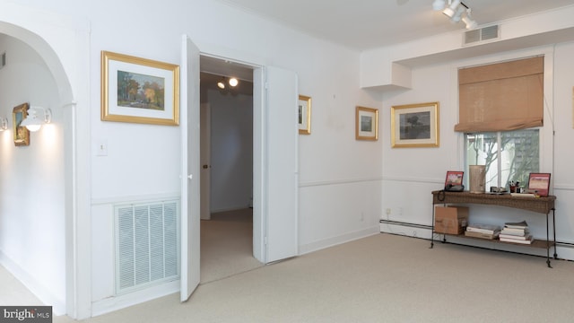 hall with rail lighting, light colored carpet, visible vents, and arched walkways