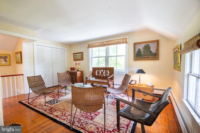 living room featuring a baseboard heating unit, vaulted ceiling, and hardwood / wood-style flooring