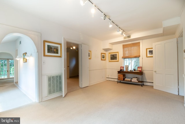 unfurnished room with visible vents, arched walkways, light colored carpet, and a healthy amount of sunlight