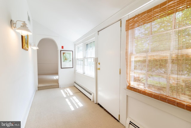 doorway with vaulted ceiling, arched walkways, baseboard heating, and light carpet