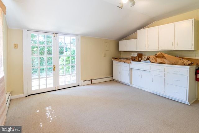 kitchen featuring light carpet, lofted ceiling, a baseboard radiator, and white cabinets