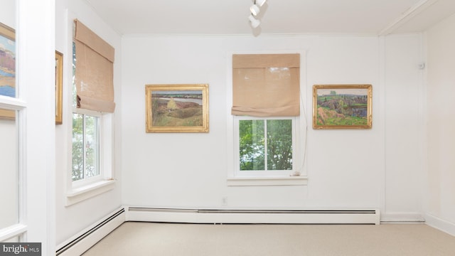 spare room featuring ornamental molding, a healthy amount of sunlight, a baseboard radiator, and carpet flooring