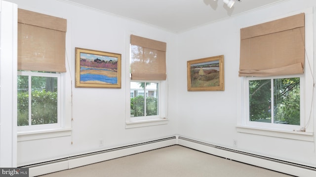 spare room featuring a baseboard heating unit, carpet flooring, and crown molding