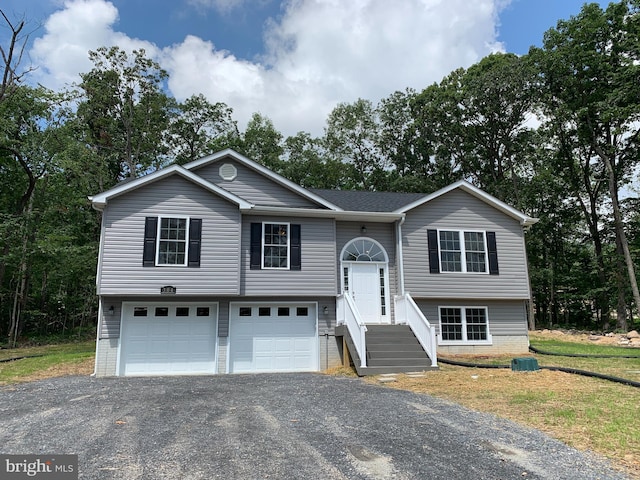 bi-level home featuring a garage, a shingled roof, and aphalt driveway