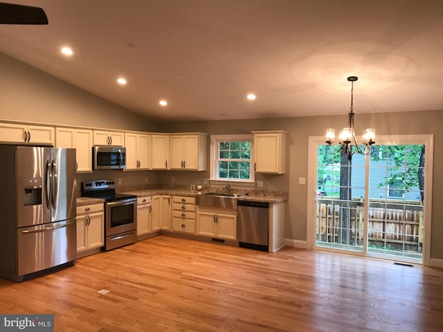 kitchen featuring a wealth of natural light, a notable chandelier, appliances with stainless steel finishes, and white cabinetry