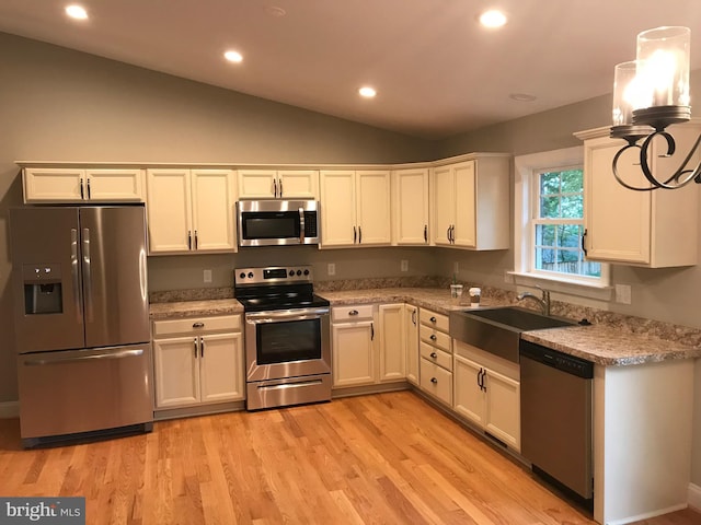 kitchen with light wood-type flooring, lofted ceiling, recessed lighting, appliances with stainless steel finishes, and a sink