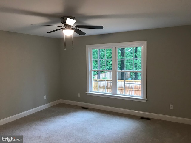 spare room featuring baseboards, visible vents, and dark colored carpet