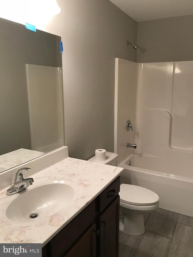 bathroom with vanity, toilet, wood finished floors, and shower / washtub combination