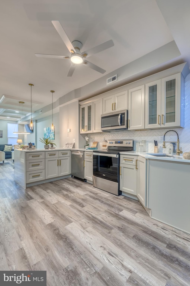 kitchen featuring appliances with stainless steel finishes, light hardwood / wood-style floors, white cabinetry, pendant lighting, and sink