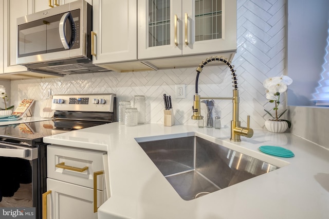 kitchen with white cabinets, stainless steel appliances, sink, and decorative backsplash