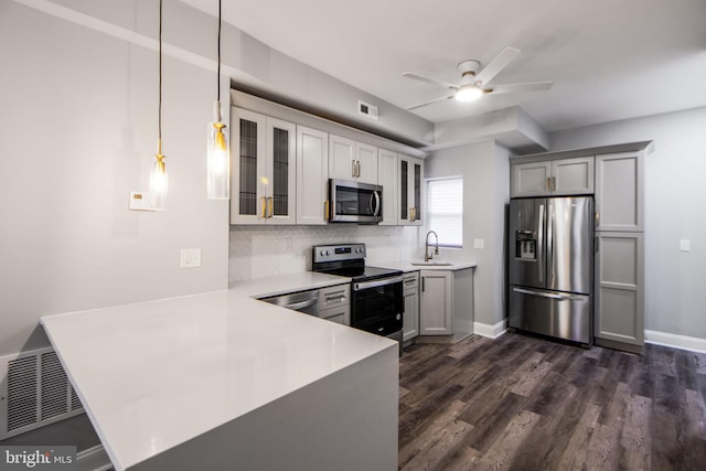 kitchen featuring dark wood-type flooring, stainless steel appliances, backsplash, decorative light fixtures, and ceiling fan