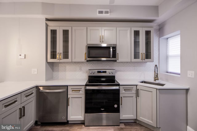 kitchen featuring dark hardwood / wood-style flooring, stainless steel appliances, decorative backsplash, and sink