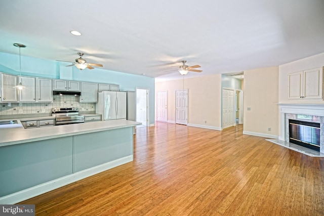 kitchen featuring white fridge, decorative light fixtures, a premium fireplace, ceiling fan, and stainless steel range with electric cooktop