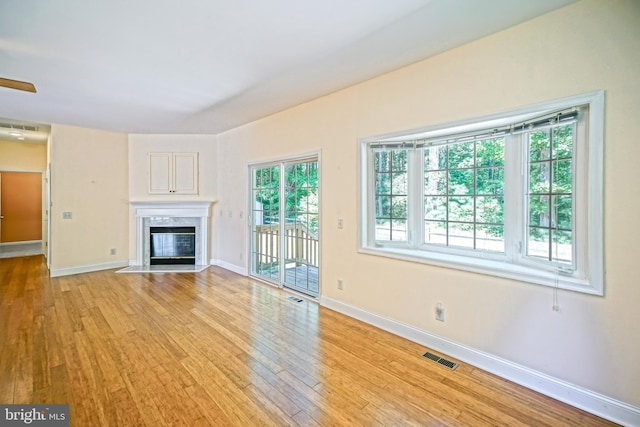 unfurnished living room with light hardwood / wood-style flooring, ceiling fan, and a high end fireplace