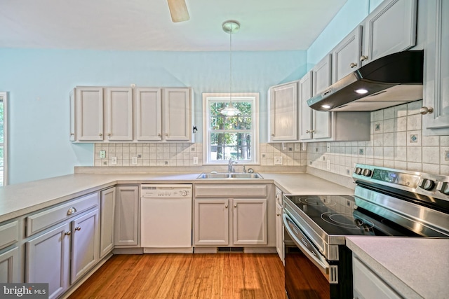 kitchen featuring stainless steel electric range oven, hanging light fixtures, white dishwasher, light hardwood / wood-style floors, and sink