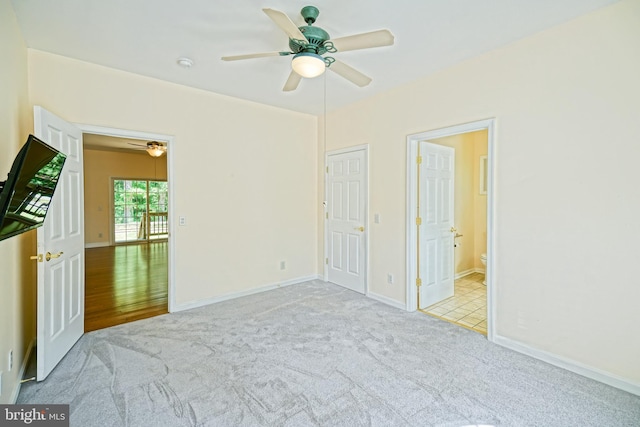 unfurnished bedroom featuring light colored carpet, ensuite bath, and ceiling fan