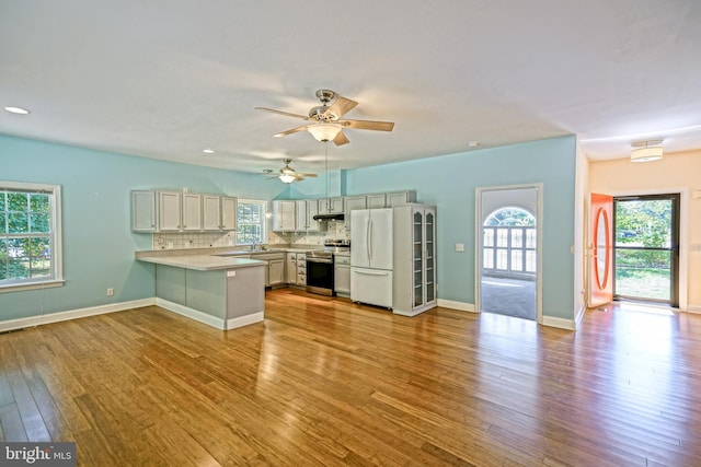 kitchen featuring light hardwood / wood-style flooring, white refrigerator, stainless steel range with electric stovetop, kitchen peninsula, and ceiling fan