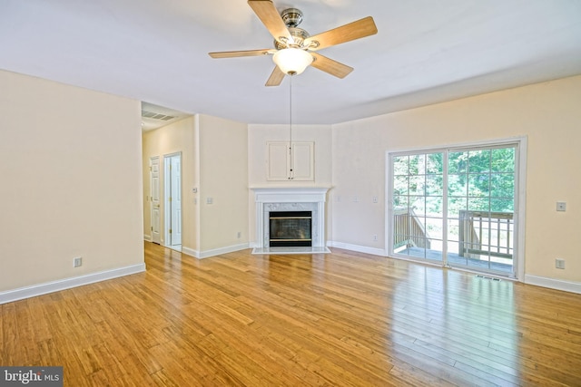 unfurnished living room with ceiling fan, a high end fireplace, and light hardwood / wood-style flooring