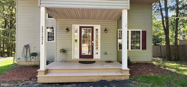 entrance to property featuring a porch and fence