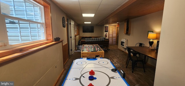 game room with a drop ceiling, dark hardwood / wood-style floors, and heating unit