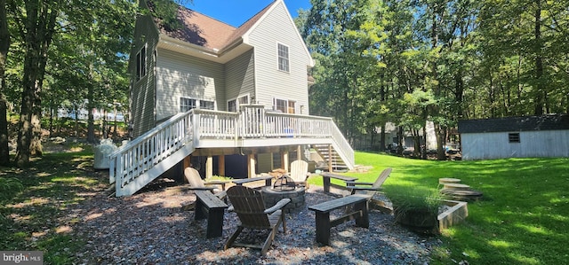 rear view of property featuring a fire pit, a yard, and a wooden deck