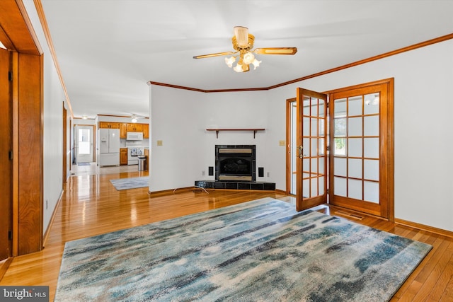 living room featuring light hardwood / wood-style floors, ceiling fan, a tile fireplace, and a healthy amount of sunlight