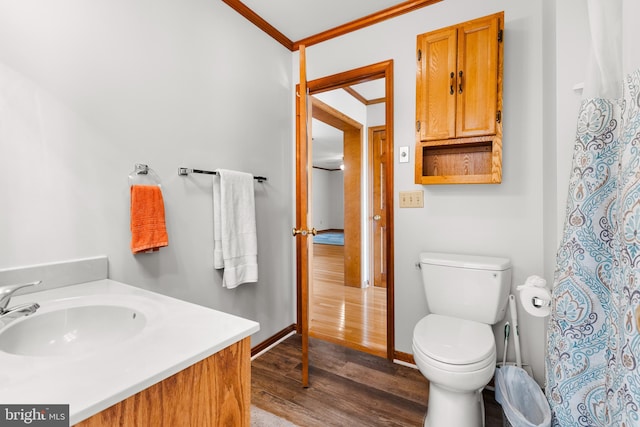 bathroom with hardwood / wood-style floors, crown molding, vanity, and toilet