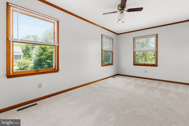 spare room with ceiling fan, light colored carpet, and crown molding