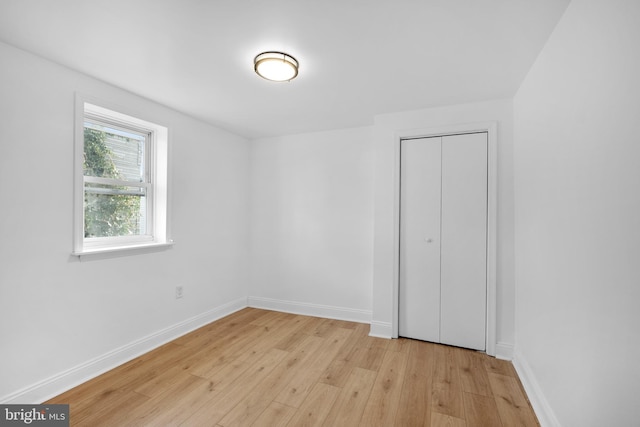 unfurnished bedroom with light wood-type flooring and a closet