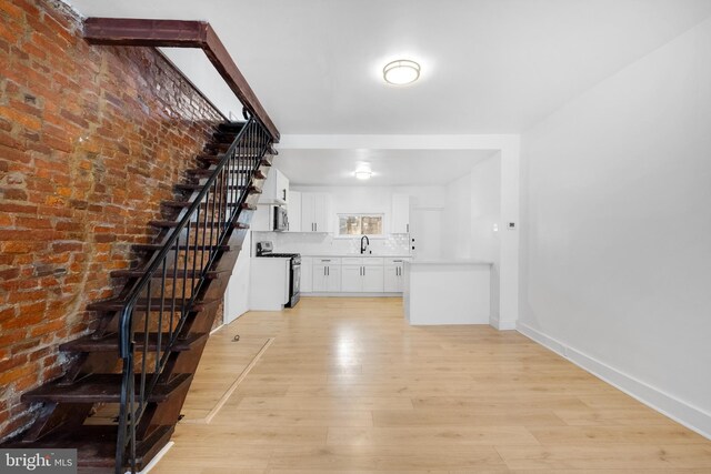 living room featuring light wood-type flooring, a fireplace, and brick wall