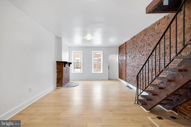 unfurnished living room featuring light hardwood / wood-style flooring and brick wall